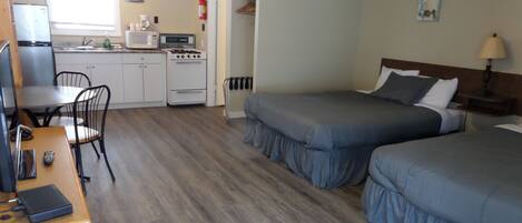 Une chambre compacte comprenant un coin cuisine, deux lits, un bureau et une chaise.