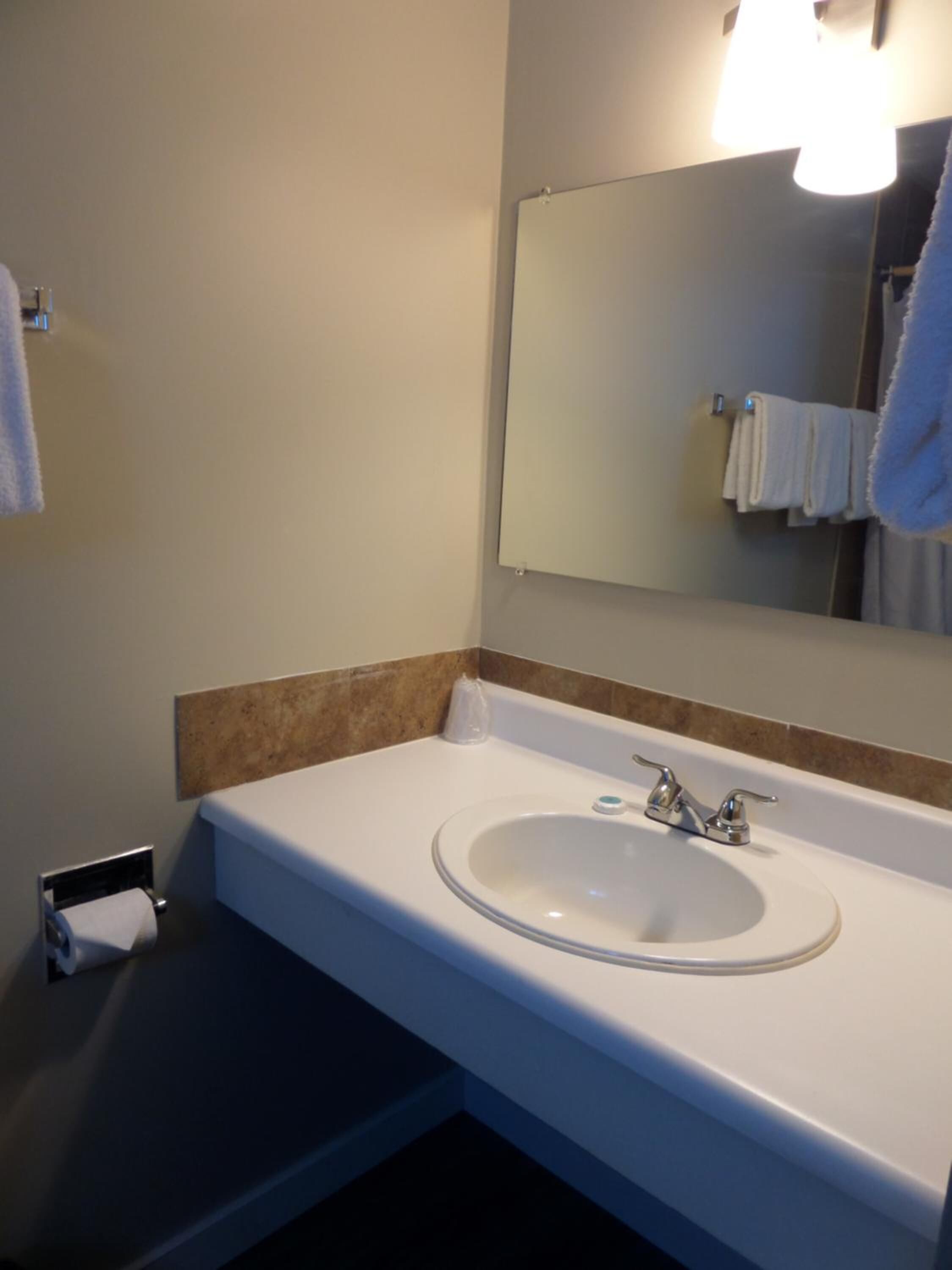 Un baño con un lavabo blanco, un espejo y un perchero para toallas.