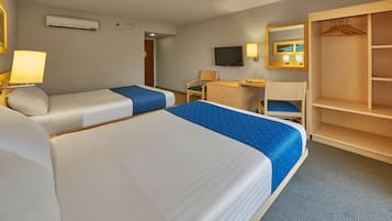 Et hotelværelse med to senge, et skrivebord, en stol, et klædeskab og et fjernsyn.