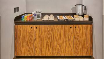 A breakfast bar with a variety of food and drink options, including cereal, juice, coffee, and pastries.