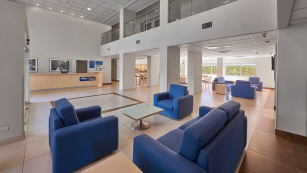 A spacious lobby with blue sofas, a reception desk, and a second-floor balcony. - City Express by Marriott Apizaco (Apizaco)