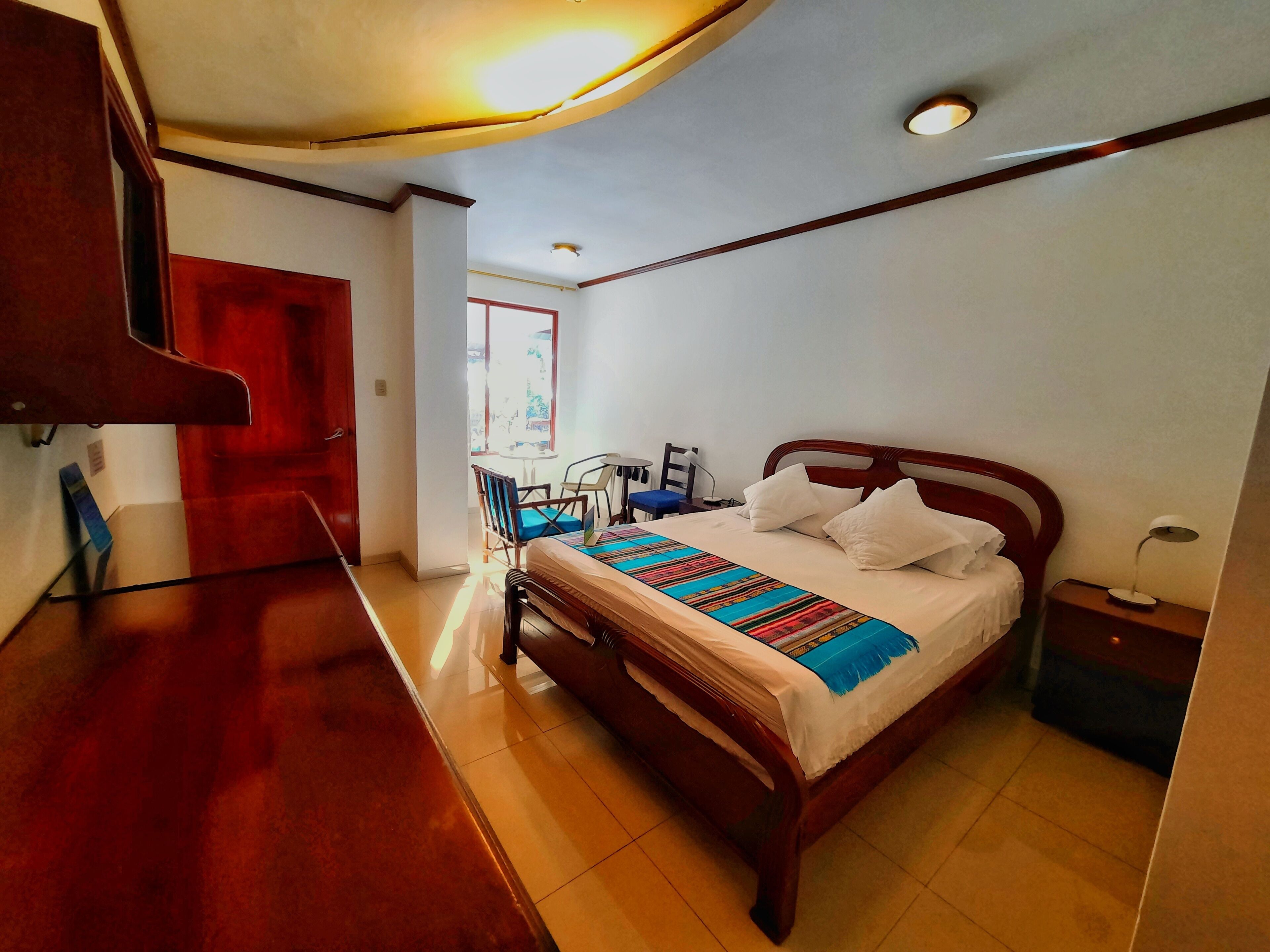 A hotel room with a wooden bed, a desk, and a chair.