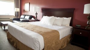 Une chambre d’hôtel avec un grand lit, un bureau, une chaise et une table de chevet avec une lampe.