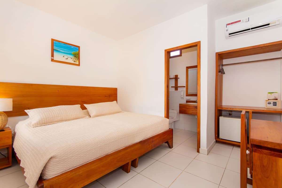 A bedroom with a wooden bed, a nightstand, a desk, and a wardrobe.