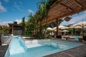 A swimming pool with a wooden pergola, lounge chairs, and umbrellas. - Hotel Fiesta (Puerto Ayora)