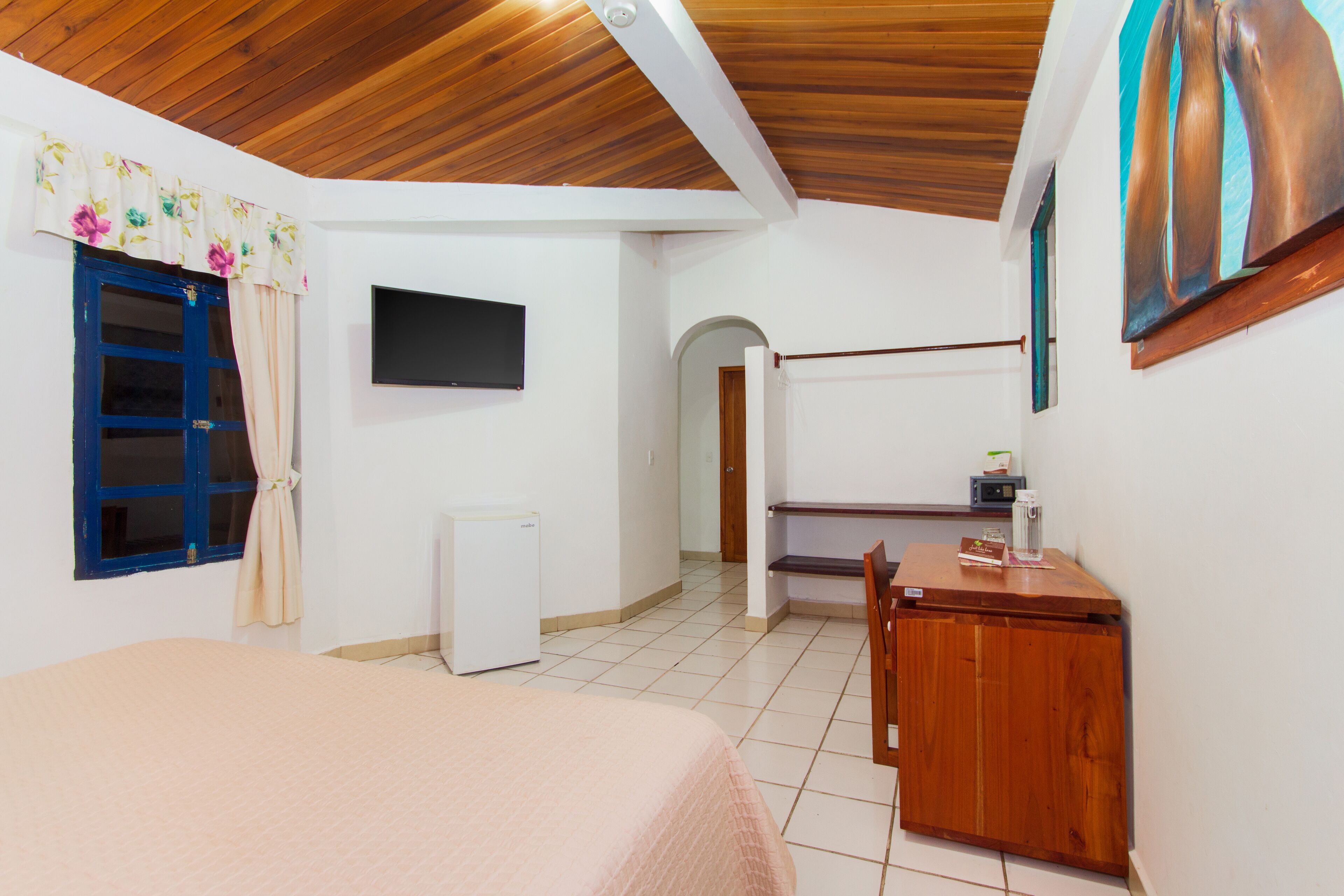Ein Zimmer mit einem Bett, einem Schreibtisch, einem Fernseher und einem kleinen Kühlschrank.