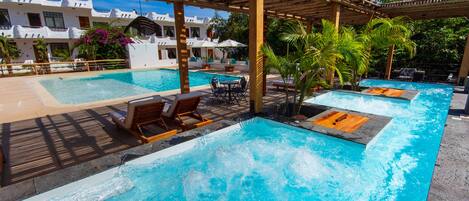 Un espace piscine avec des chaises longues et une pergola.