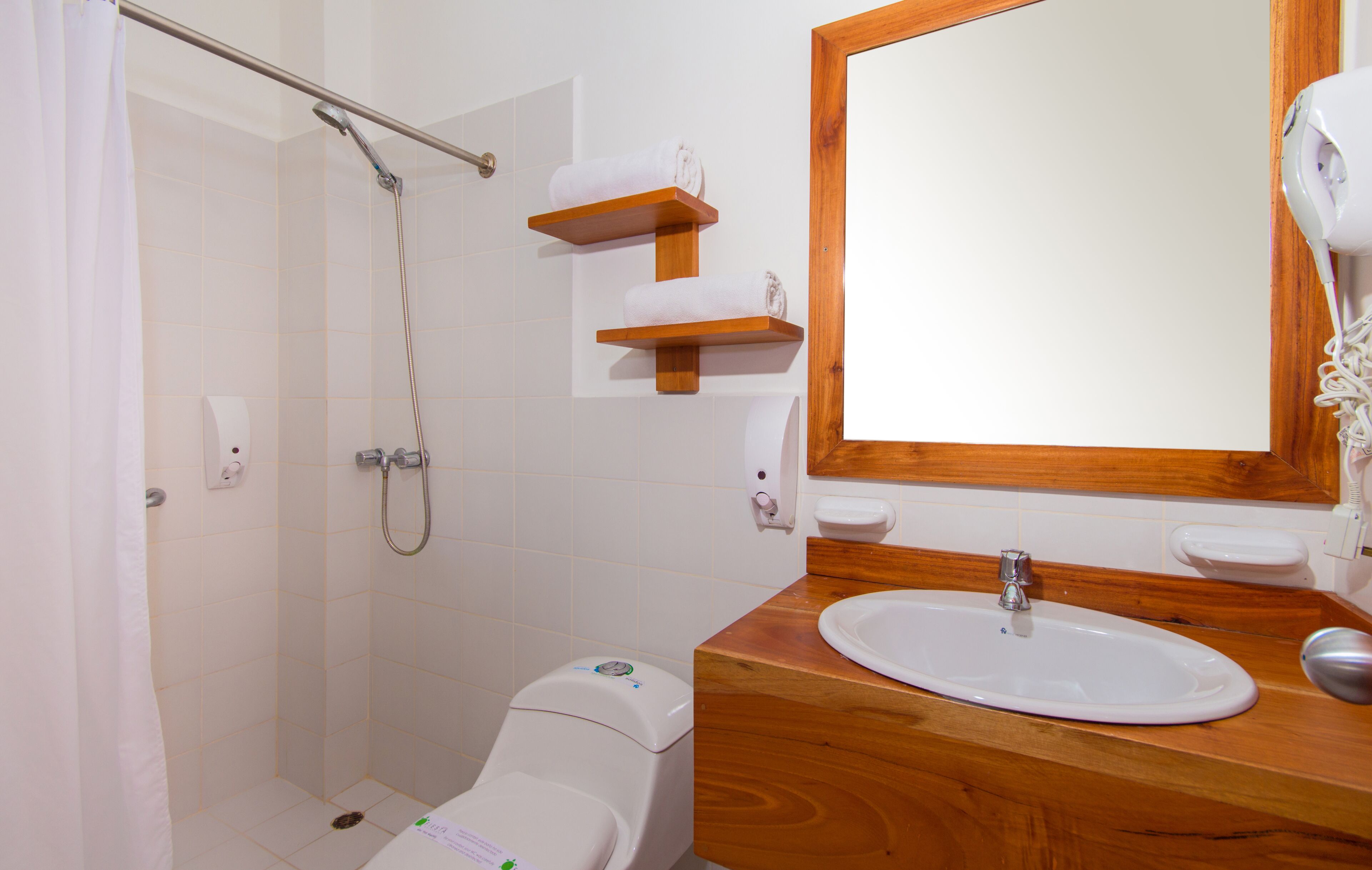 Ein Badezimmer mit Dusche, Toilette, Waschbecken und Holzregalen.