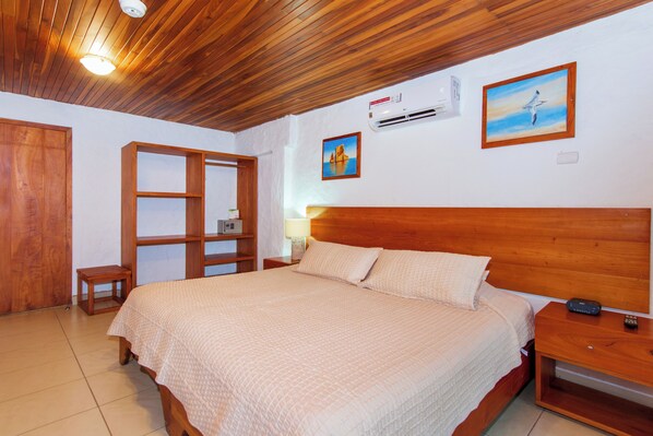 Un dormitorio con una cama de madera, una mesita de noche, una pequeña mesa, un armario y un cuadro en la pared.