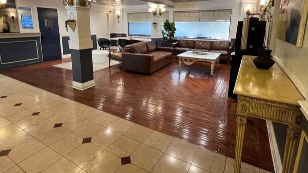 A spacious lobby with a wooden floor, a brown leather sofa, a white coffee table, and a reception desk with a TV. - Rotex Western Inn (Los Angeles)