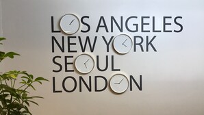 A wall with clocks and text listing cities. - Rotex Western Inn (Los Angeles)