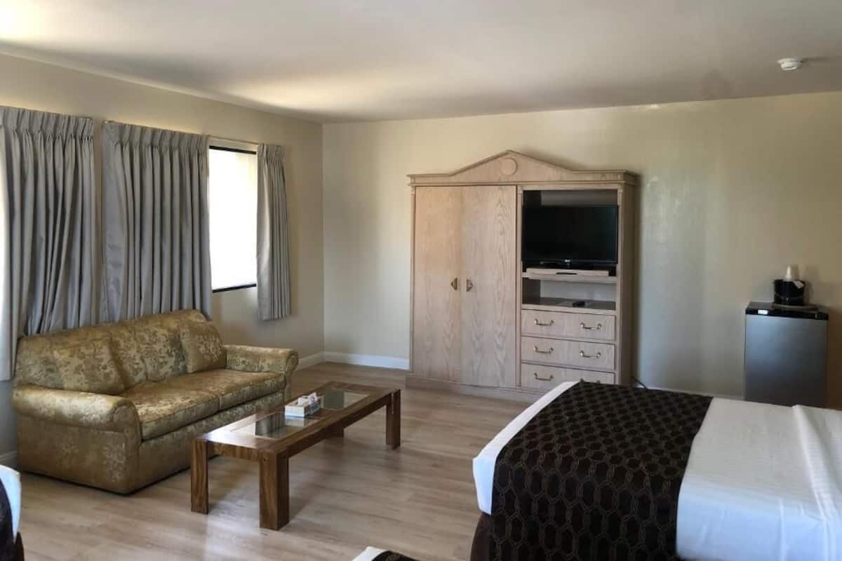 A hotel room with a sofa, a coffee table, a TV cabinet, and a bed.