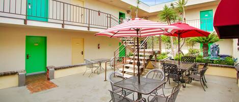 A courtyard with outdoor seating, a staircase, and a green door.