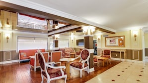 A spacious lobby with a high ceiling, multiple seating areas, and a large screen. - Rotex Western Inn (Los Angeles)