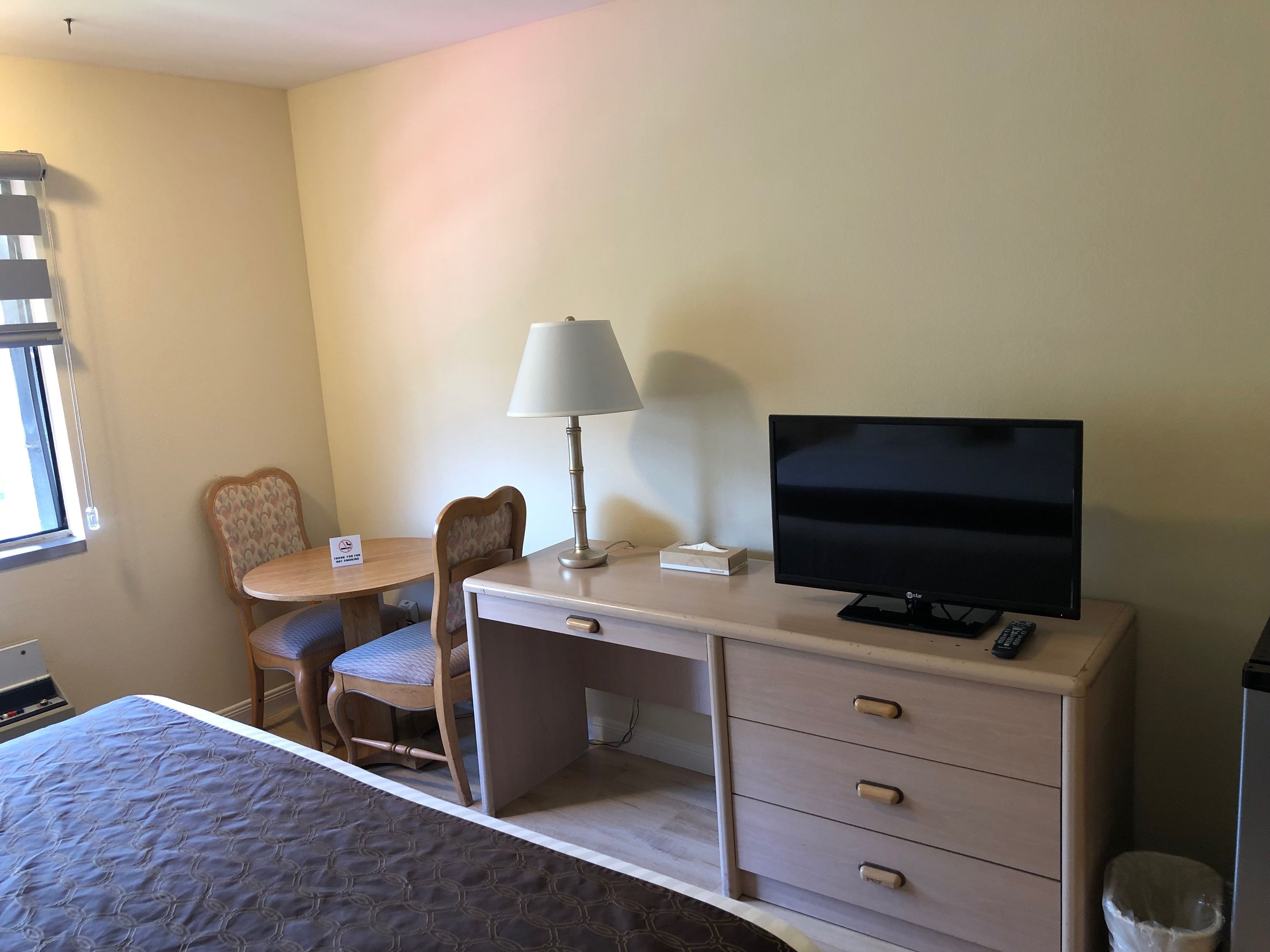 Une chambre d’hôtel avec un lit, un bureau avec une lampe, une télévision et une chaise.