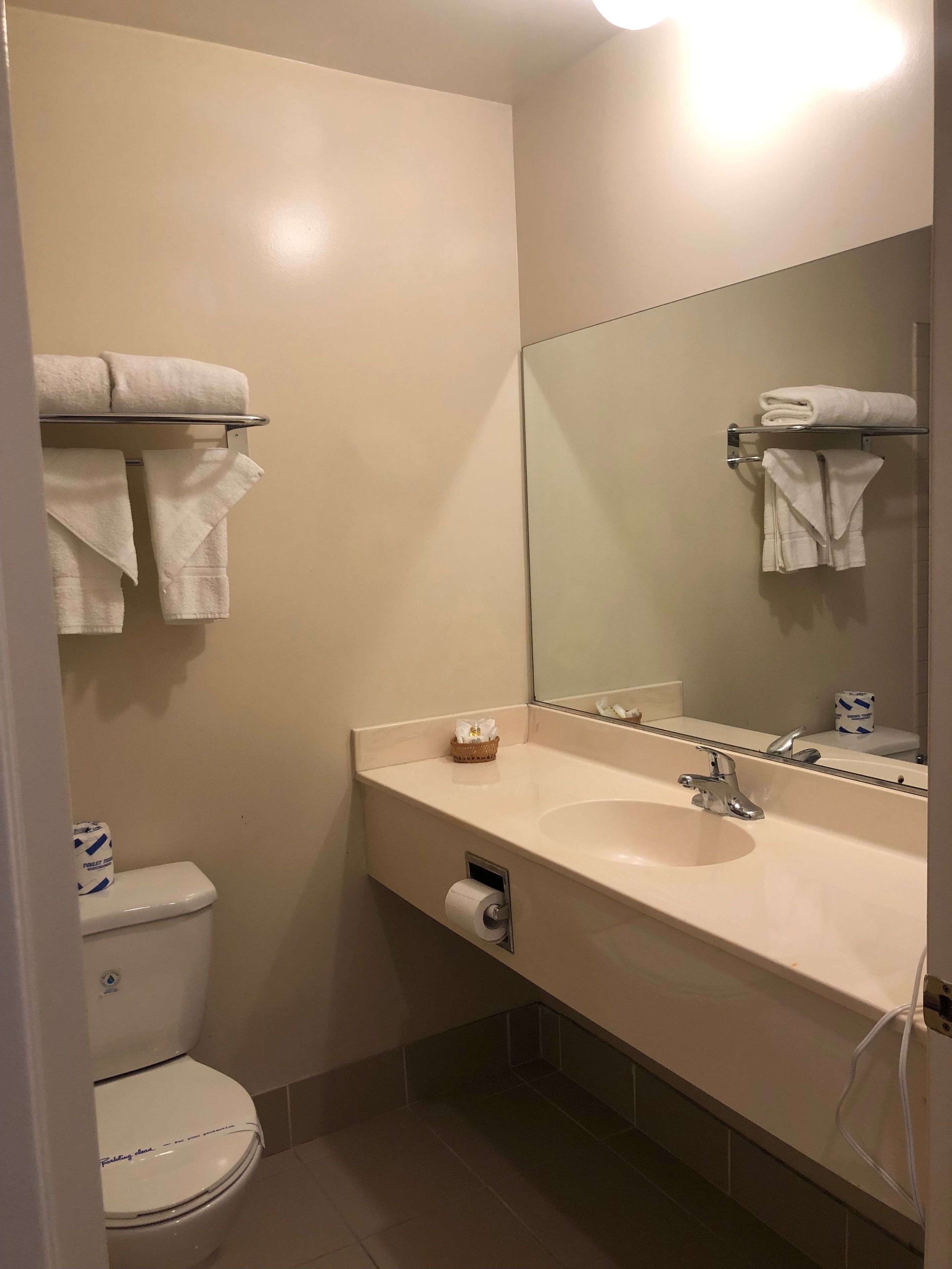Un bagno con il water, un lavandino, uno specchio e asciugamani su un porta-asciugamani.