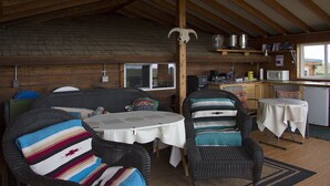 Un chalet rustique comprenant un coin repas, une cuisine et un espace détente avec des coussins à rayures.