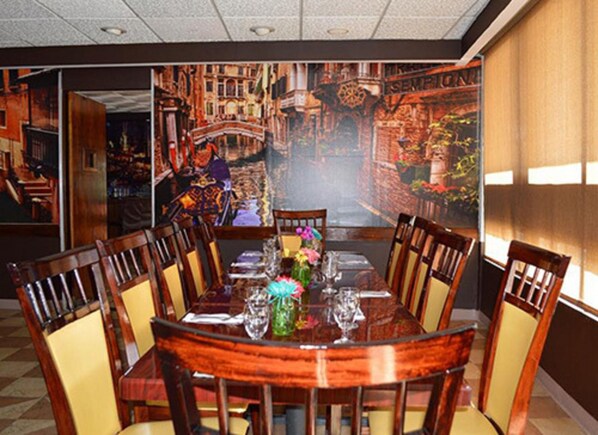 A dining area with a large mural of a cityscape, a round table with chairs, and a vase with flowers.