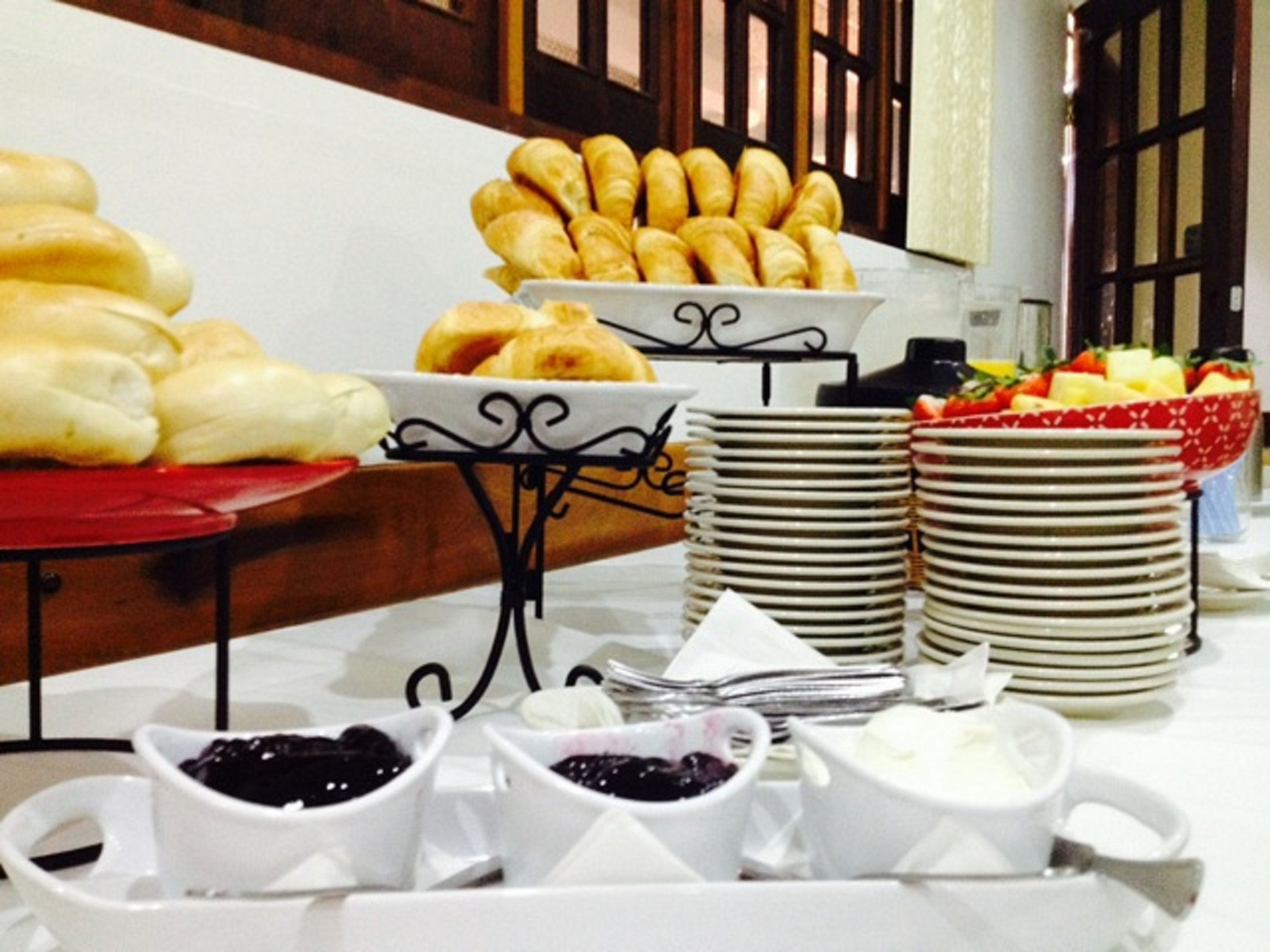Un buffet proposant une variété d’aliments, notamment du pain, des pâtisseries et des fruits.