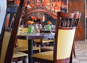 A dining table set with chairs, glasses, and vases with flowers.
