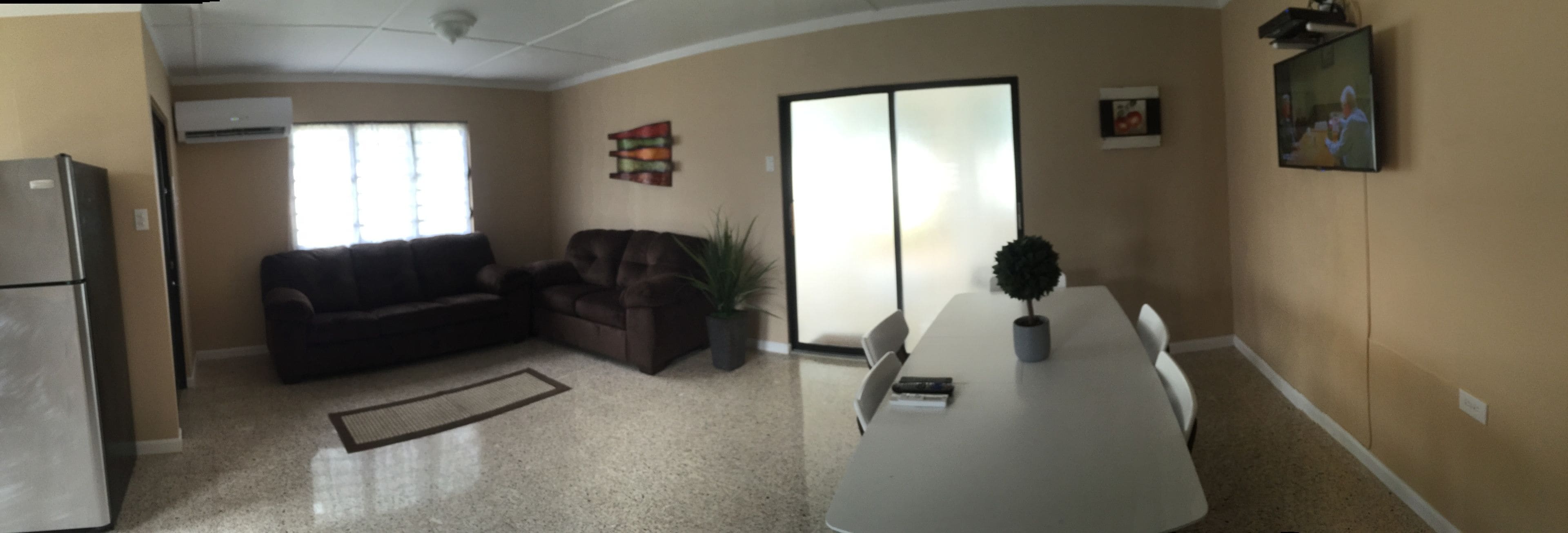 A living room with a sofa, a coffee table, and a TV. There is a sliding door leading to another room.