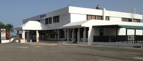 Un edificio de dos pisos con techo plano y un letrero que dice "Arecibo Inn".