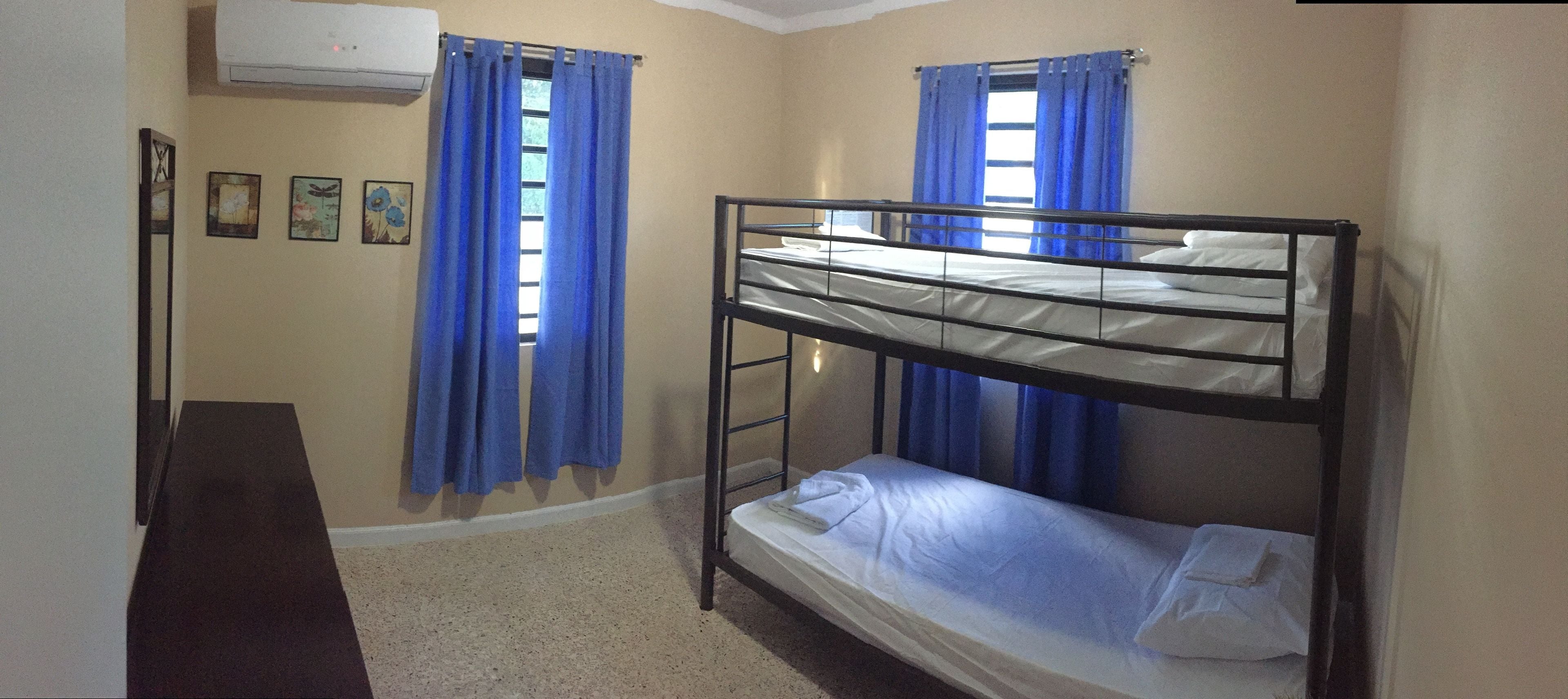 A room with bunk beds, a desk, and curtains.