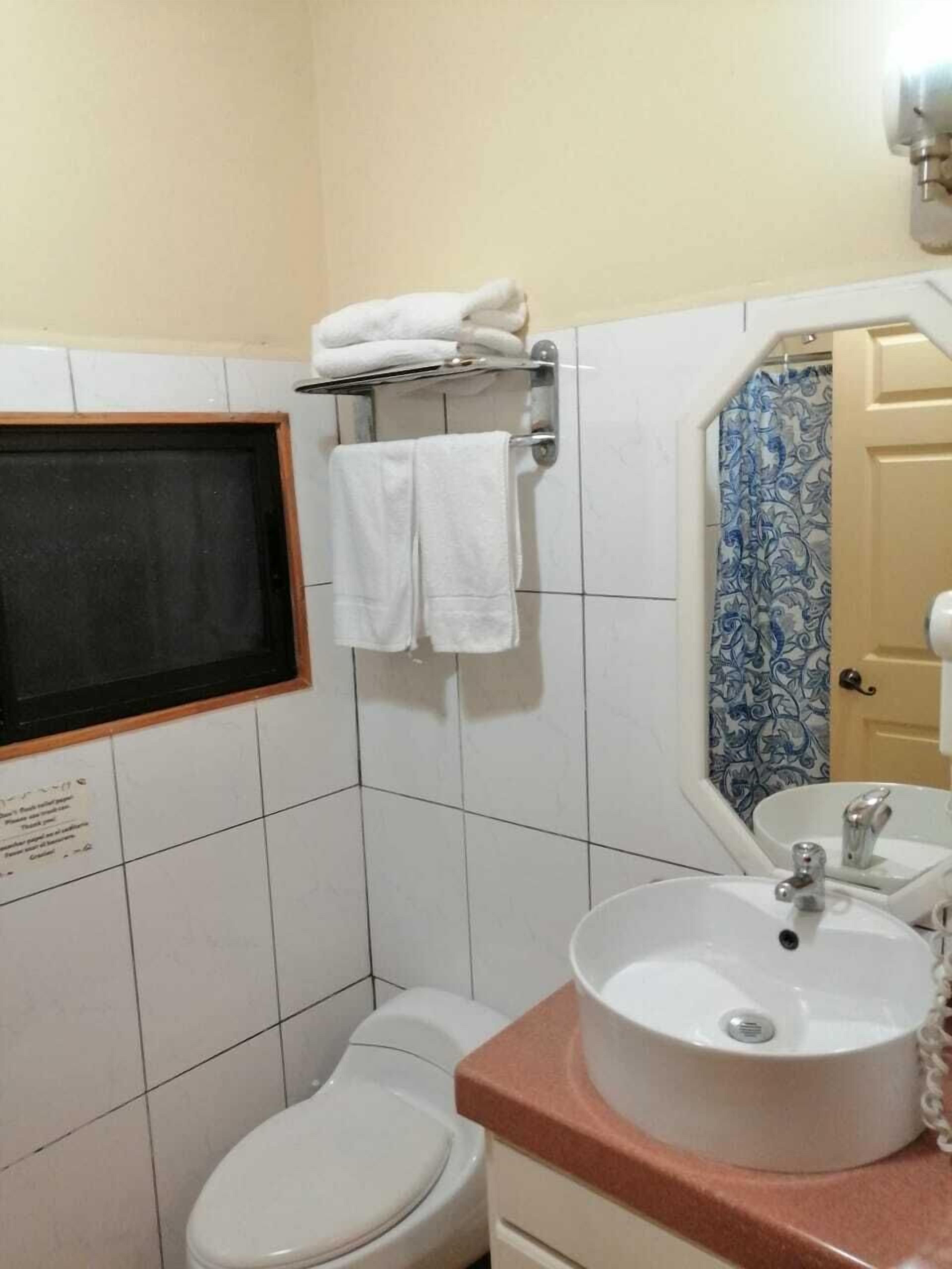 A bathroom with a toilet, sink, and towel rack.