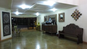 A spacious living area with a tiled floor, a wooden bench, a dining table with chairs, and a cabinet with decorative items. - Apartotel Don Francisco (San Rafael)