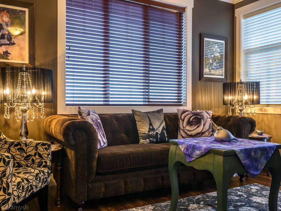 Una sala de estar acogedora con un sofá marrón, un sillón estampado y una mesa con mantel morado.