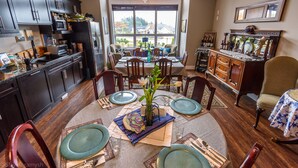 A dining area with a large window, dark wooden cabinets, and a chandelier. - Brookside Inn Boutique Hotel (Abbotsford)