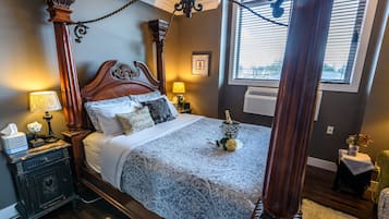 A four-poster bed with a canopy, a nightstand with a lamp, and a vase with flowers on the side table.