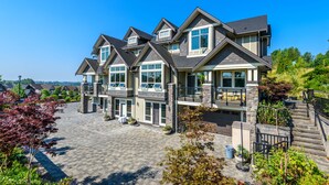 A multi-story residential building with a stone facade, large windows, and a landscaped driveway. - Brookside Inn Boutique Hotel (Abbotsford)