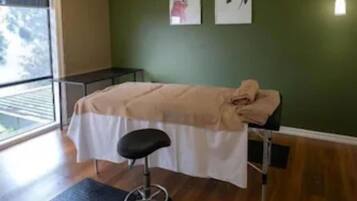 Relax in this serene space with a massage table, artworks, and a large window.