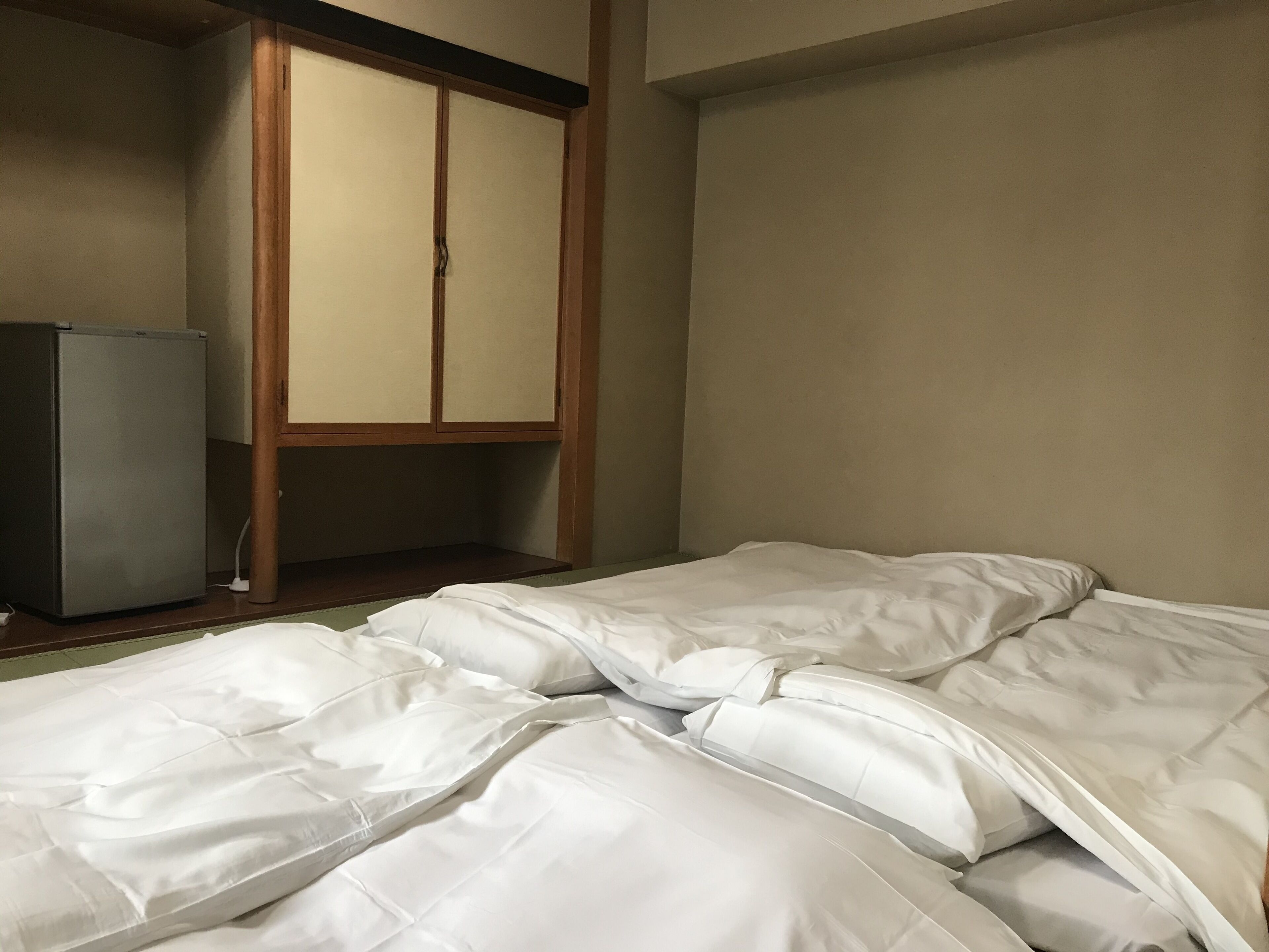 Een hotelkamer met een bed, een kledingkast en een kleine koelkast.