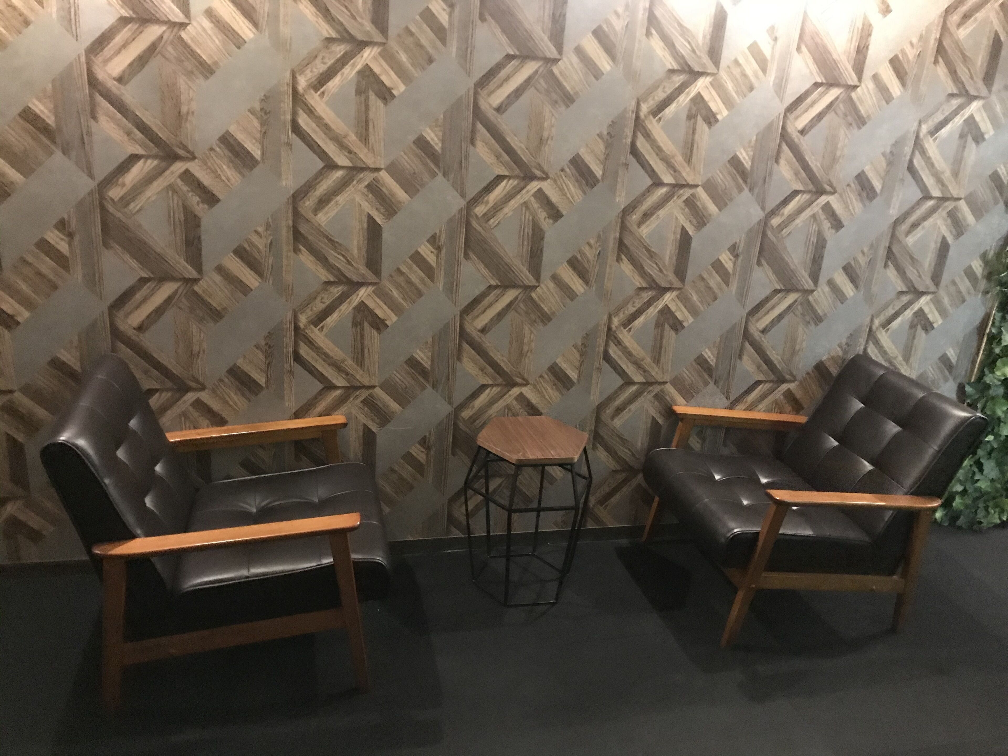 Una habitación con dos sillones de cuero, una mesita de madera y un papel tapiz estampado.