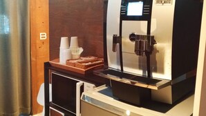 A coffee machine with a display screen, a coffee cup holder, and a basket of napkins. - Tabist THE GREEN OTARU (Otaru)