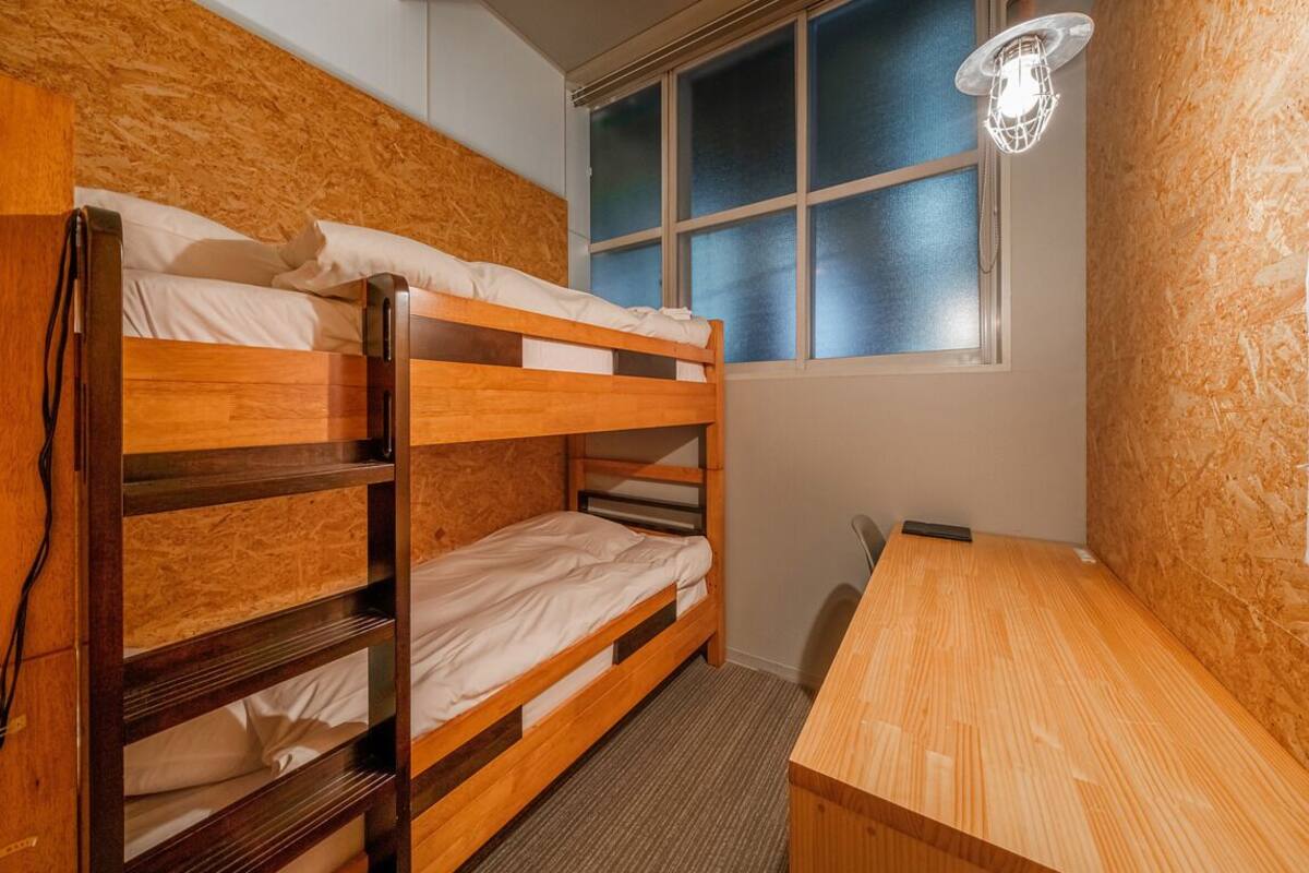 A bunk bed room with a desk and a window.
