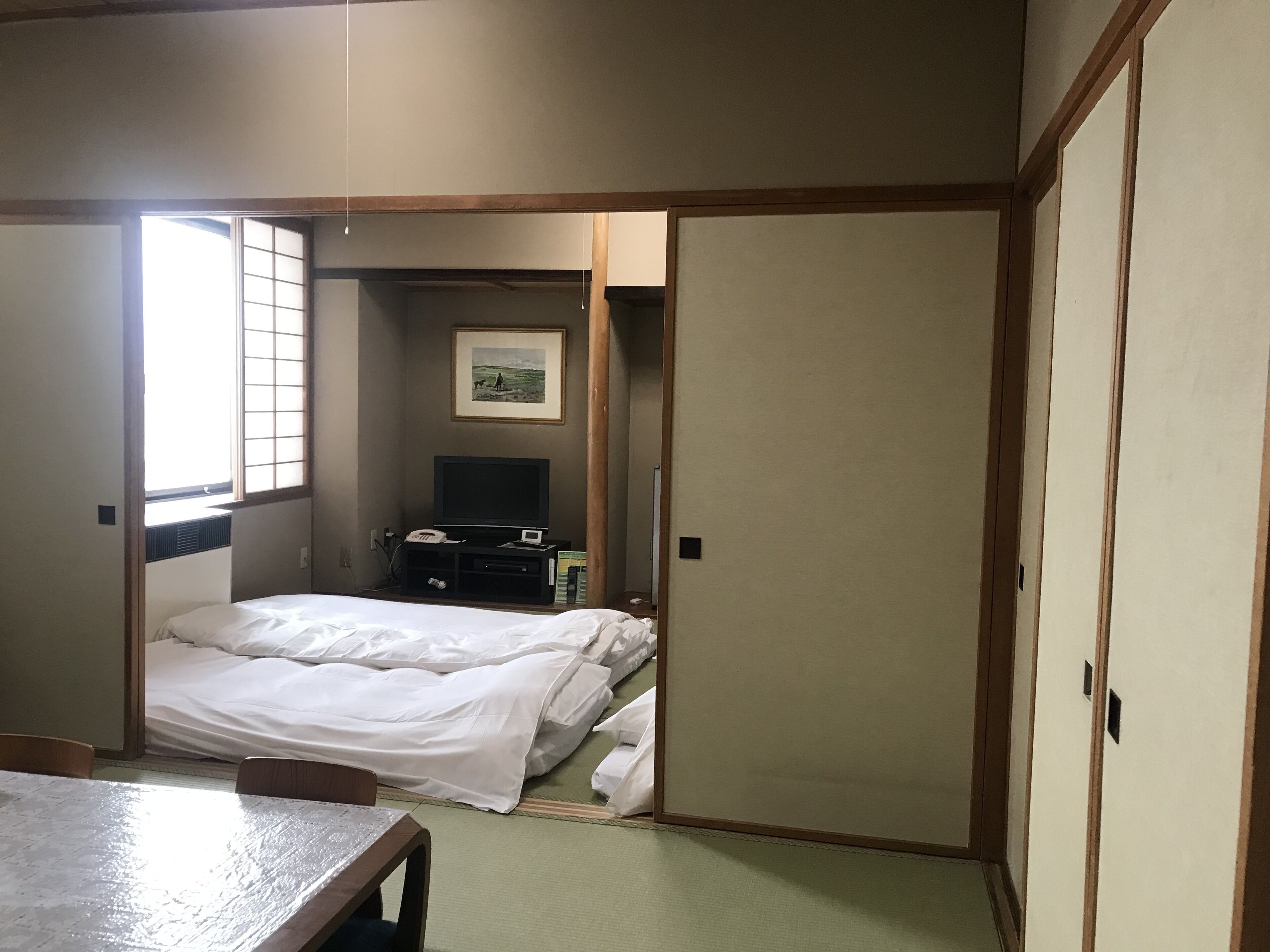 A hotel room with a bed, a desk, a TV, and a picture on the wall.