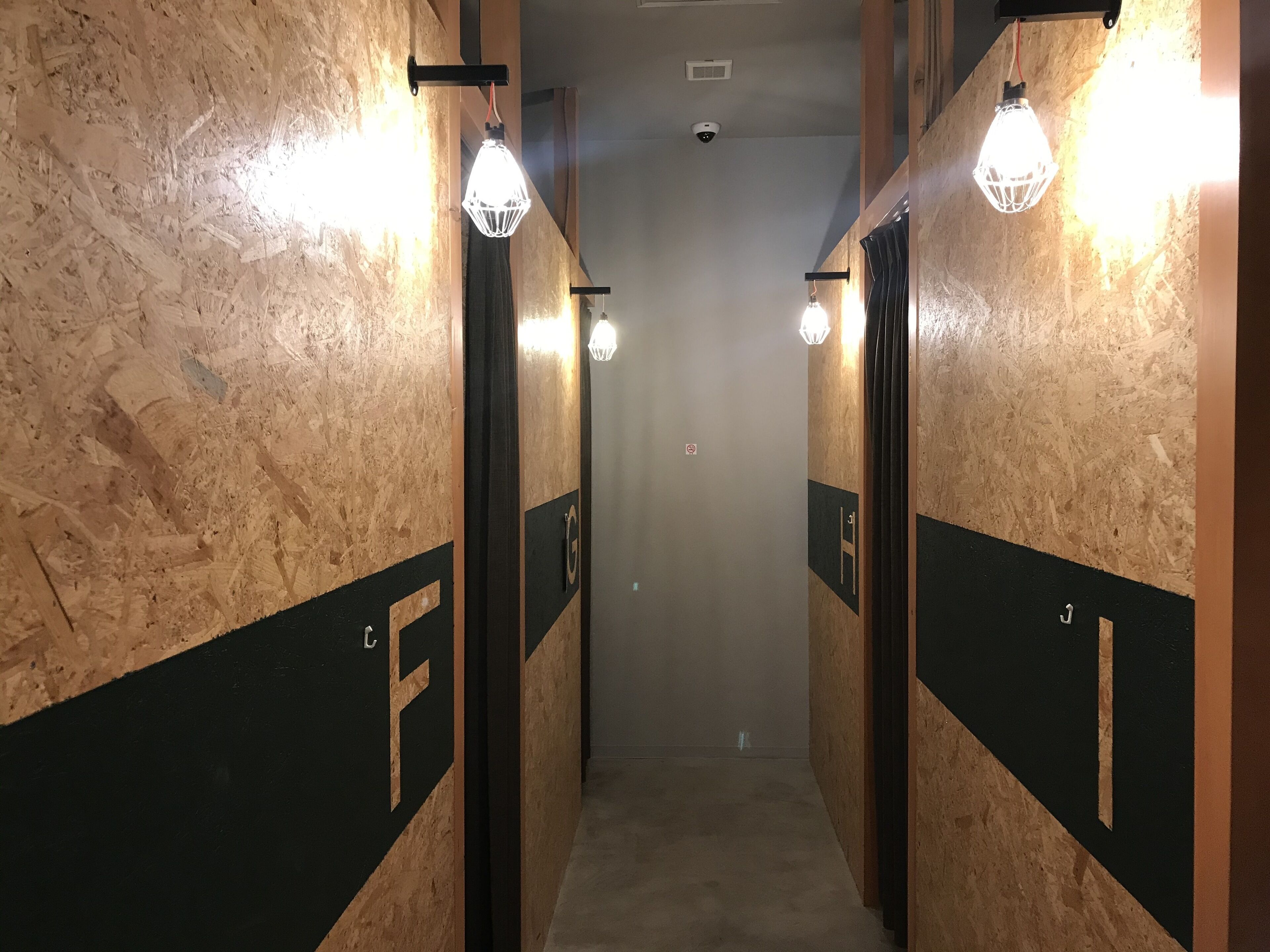 A hallway with wooden walls and black panels marked with letters.