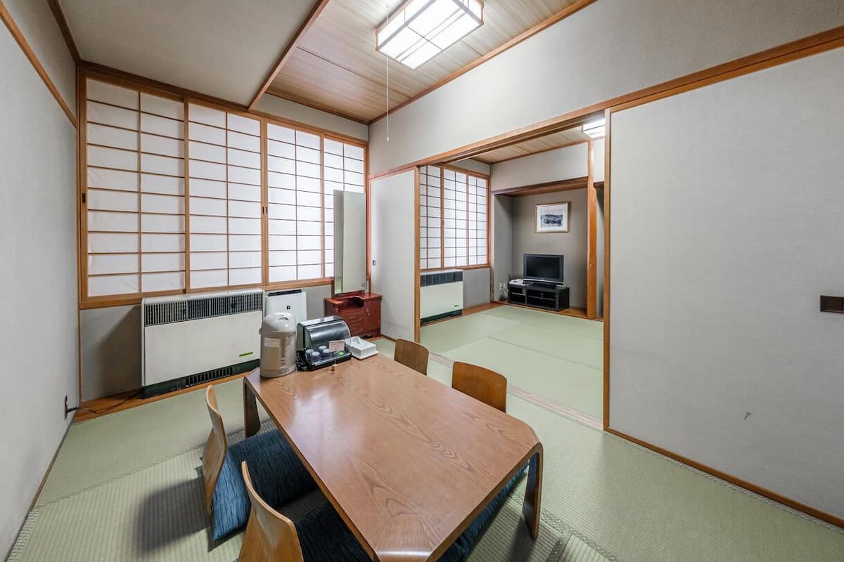 A traditional Japanese-style room with tatami flooring, a low wooden table, and sliding shoji doors.