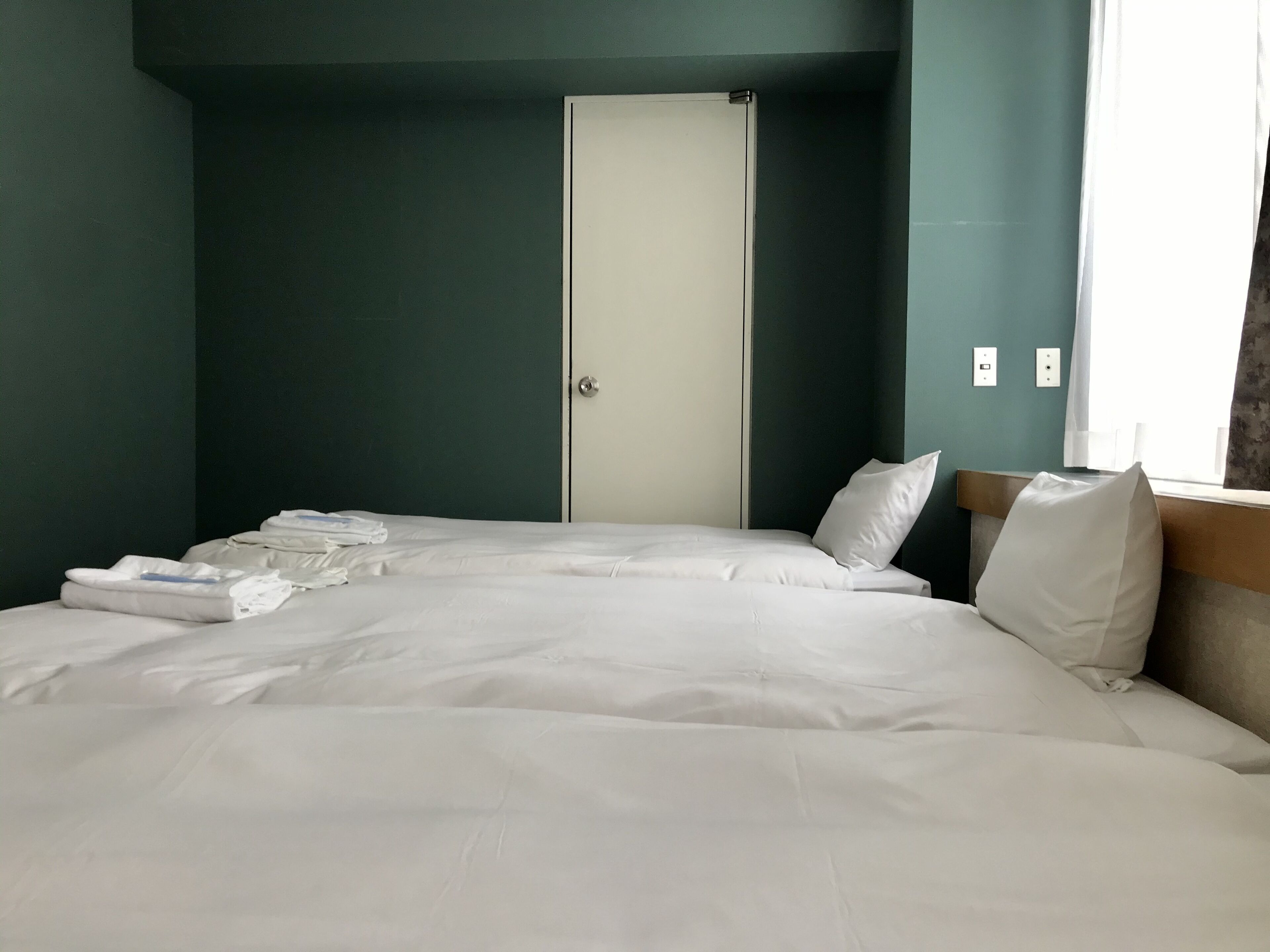 A hotel room with a bed, a wardrobe, and a window.