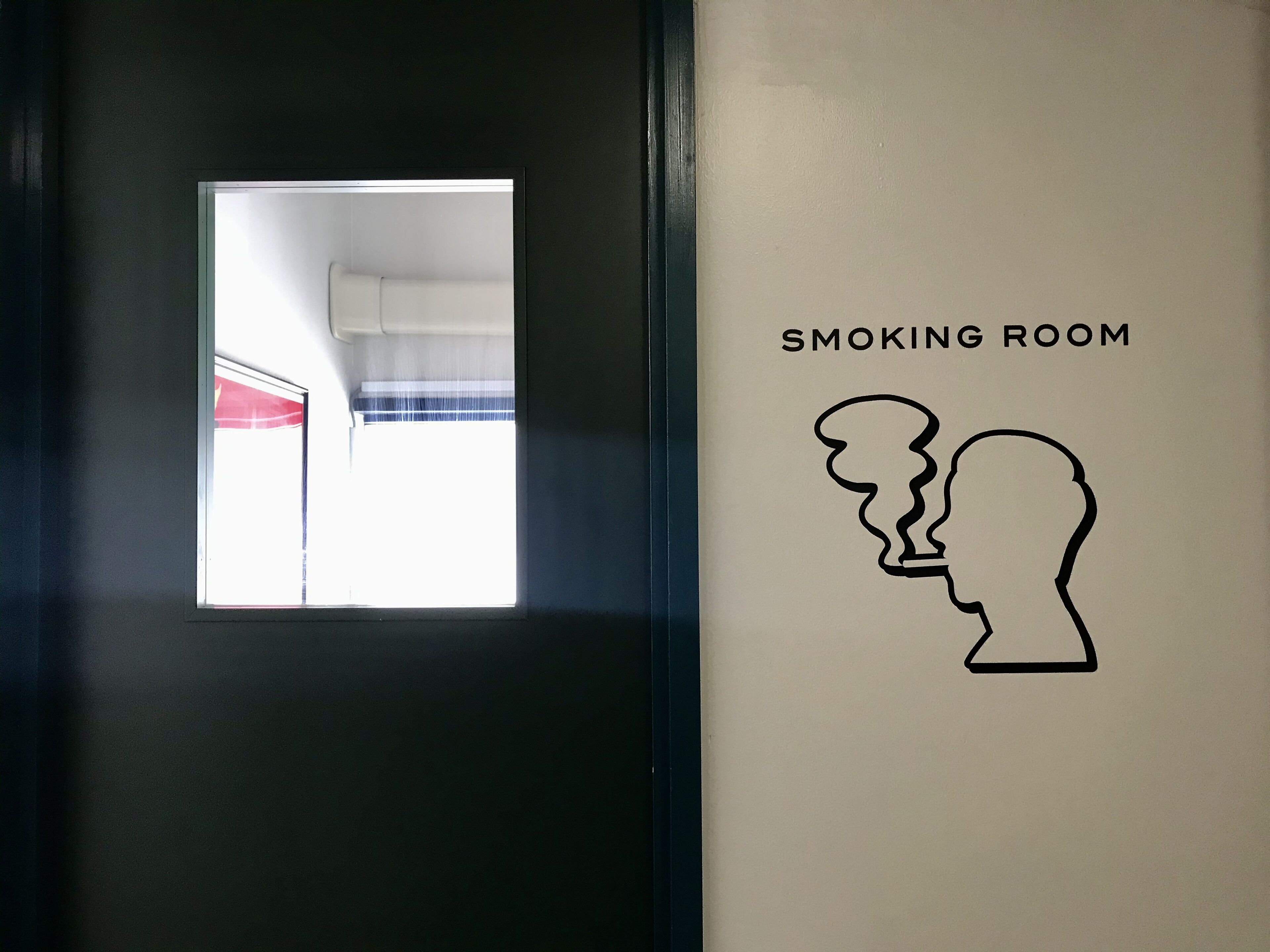 A door with a window and a wall sign indicating a smoking room.