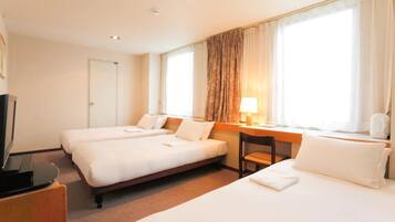 A hotel room with two beds, a desk, a chair, a TV, and a window with curtains.