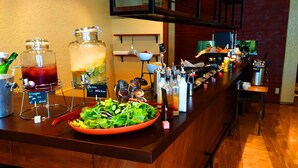 A bar area with a salad bowl, a drink dispenser, and various condiments. - Tabist THE GREEN OTARU (Otaru)