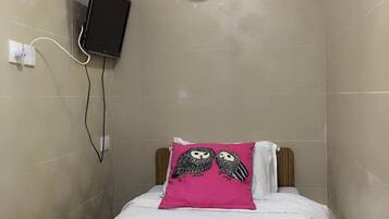 A small hotel room with a bed, a wall-mounted TV, a clock, and a toilet paper dispenser.
