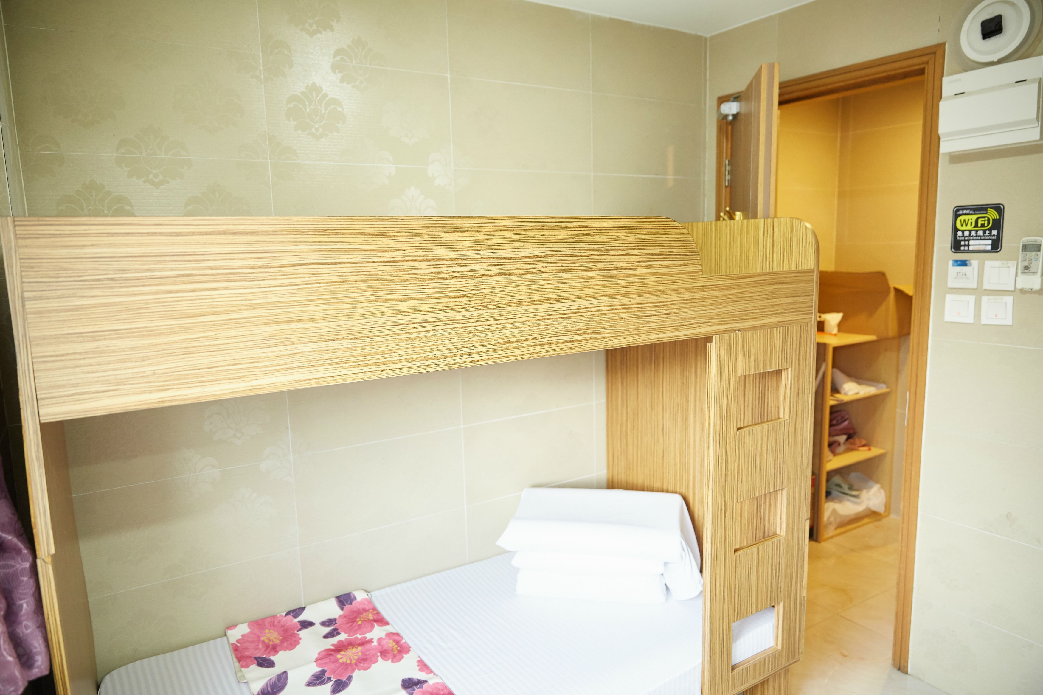 A bunk bed with a wooden headboard, a small bedside table, and a floral-patterned bedspread.