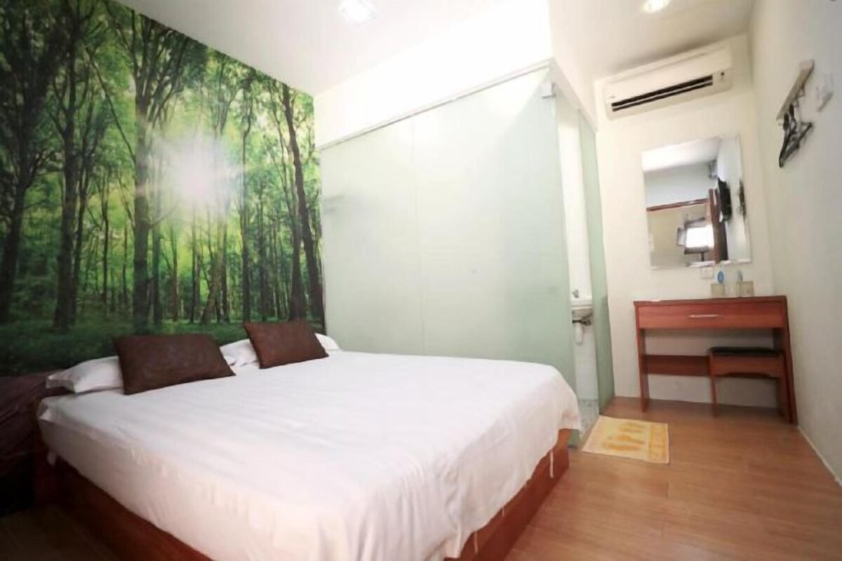 Quarto com cama, penteadeira, espelho e parede com um mural de floresta.