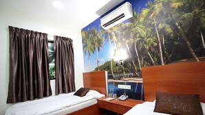 A hotel room with two beds, a wooden headboard, an air conditioner, a nightstand, and a wall mural of palm trees. - Rain Forest Hotel (Kuala Lumpur)