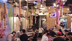 A restaurant with patrons seated at tables, copper pipes, and hanging spherical decorations. - Rain Forest Hotel (Kuala Lumpur)